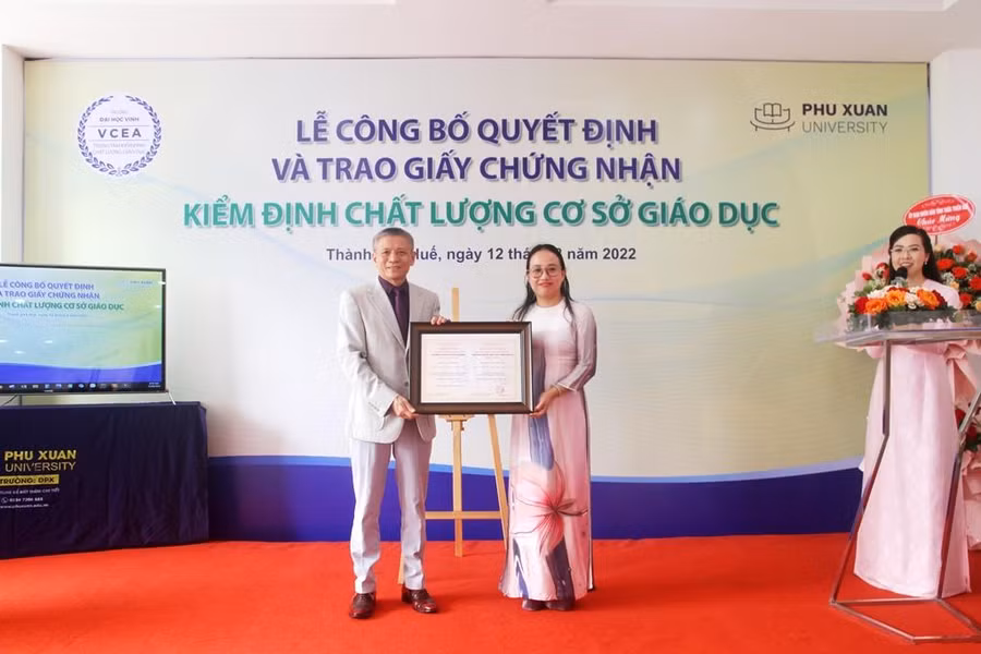 Đại diện Trung tâm kiểm định chất lượng giáo dục - Đại học Vinh (bên trái) trao giấy chứng nhận kiểm định chất lượng cơ sở giáo dục (có giá trị 5 năm) cho Trường ĐH Phú Xuân.