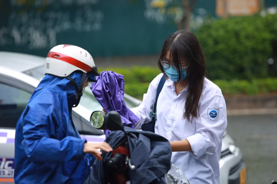 Vào khoảng 13h, trời Hà Nội có mưa, nhiều phụ huynh mặc áo mưa để đưa con em mình tới điểm thi.
