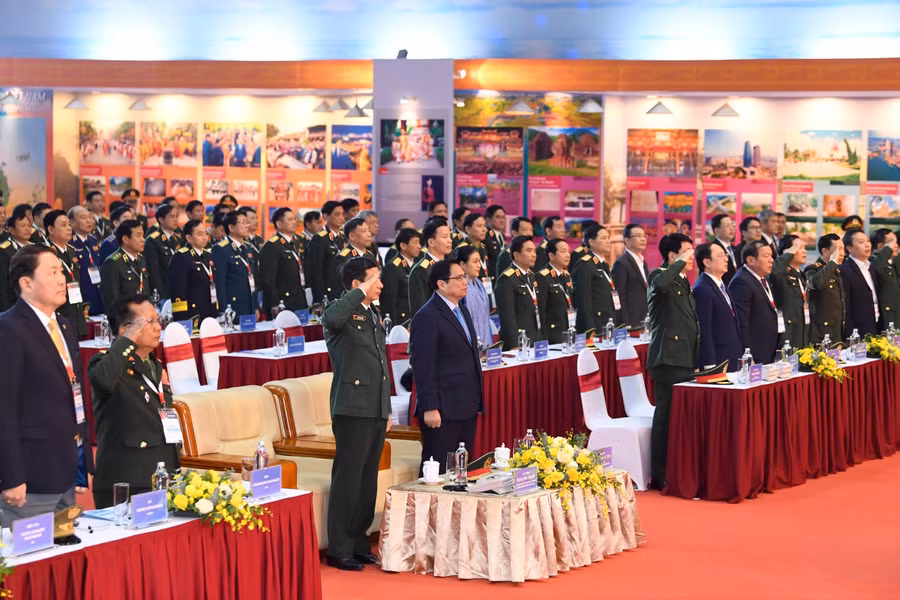 Các đại biểu dự khai mạc triển lãm thực hiện nghi thức chào cờ.