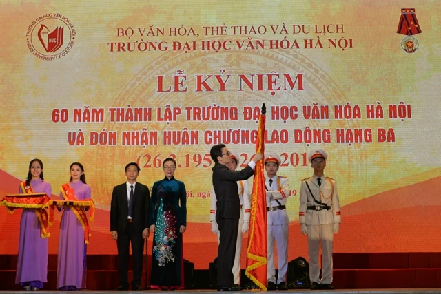 Phó Thủ tướng Vũ Đức Đam gắn Huân chương Lao động hạng Ba lên lá cờ truyền thống nhà trường