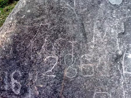 Kẻ vô ý thức vạch cả số hiệu đè lên những đường nét trên đá…