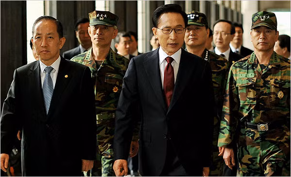 President Lee Myung-Bak of South Korea, center, walked to a news conference with defense minister Kim Tae-Young, left, in Seoul on Monday