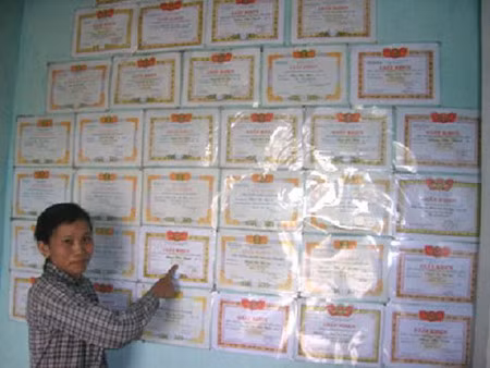 Mẹ Thịnh bên những thành tích của Thịnh trong 9 năm học vừa qua