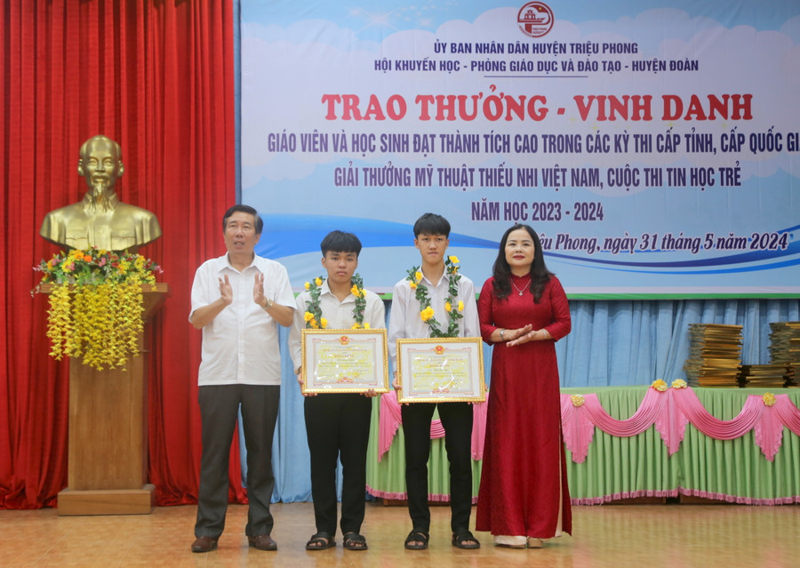 TS Lê Thị Hương, Giám đốc Sở GD&ĐT tỉnh Quảng Trị; ông Nguyễn Hữu Ngọc, Phó Bí thư Thường trực Huyện ủy Triệu Phong tặng Bằng khen của UBND tỉnh cho 2 học sinh.