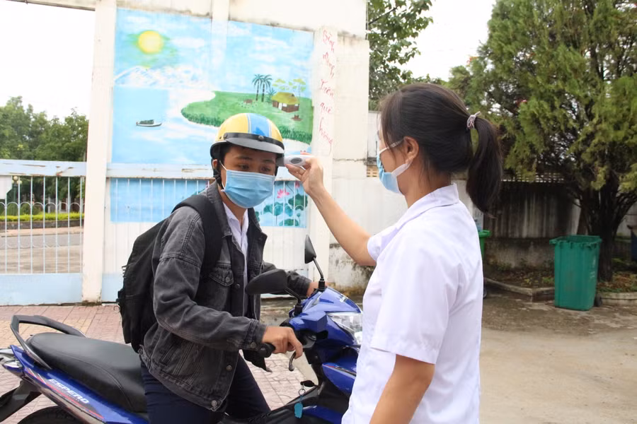 Học sinh được đo thân nhiệt , sát khuẩn trước khi vào phòng thi.