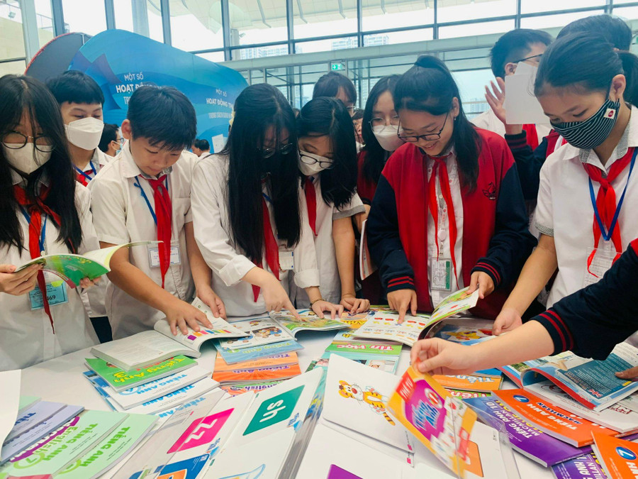 Trình Lê Chí Anh - học sinh lớp 7A6, Trường THCS Mỹ Đình (Hà Nội) (thứ 3 từ trái sang phải) và các bạn hào hứng xem sách giáo khoa tại triển lãm.