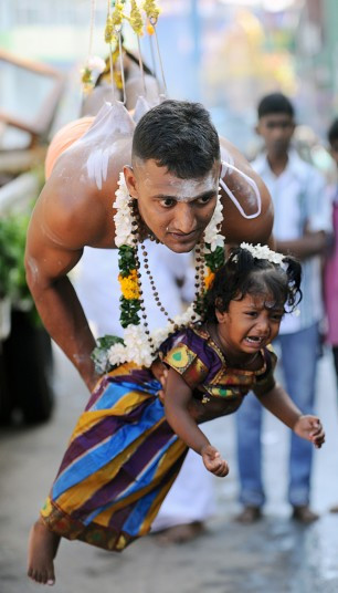 A Sri Lankan Tamil Hindu, suspended with hooks pierced through his body, carries a child while participating in the Vel Hinduism festival in Colombo. Ethnic Tamils, who are mainly followers of Hinduism, are the main minority community in the island which is emerging from nearly four decades of ethnic conflict which had claimed up to 100,000 lives.