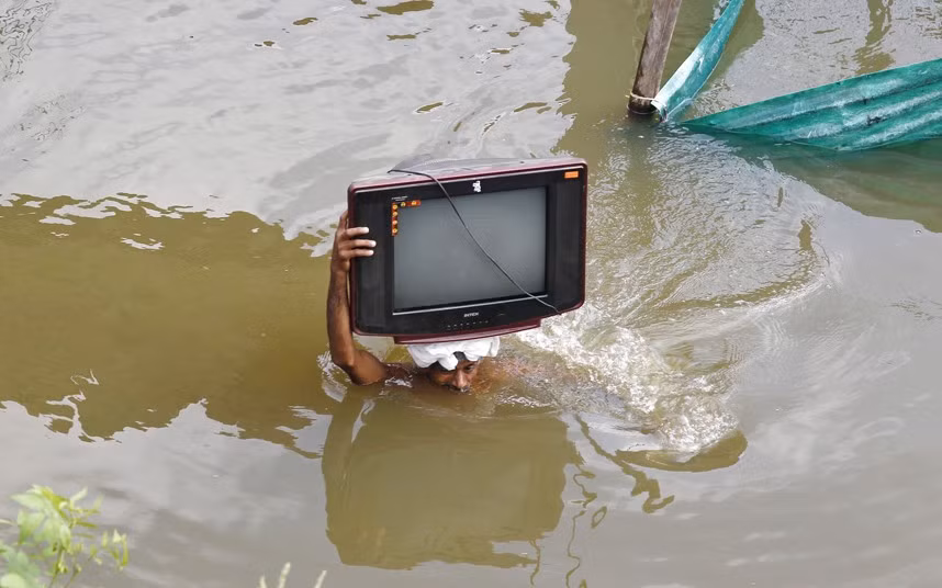 A flood-affected man carries his television set to a safer place, after heavy monsoon rains caused a rise in the water levels of the river Ganges, in city of Allahabad, India.