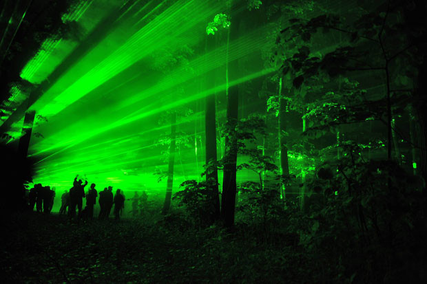 People are pictured in Balotesti forest in Hungary illuminated by lasers to listen techno music and to dance in an annual event