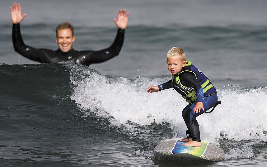 Triston Gailey, 3, surfs a wave as his father, Todd, watches in Morro Bay, California, USA