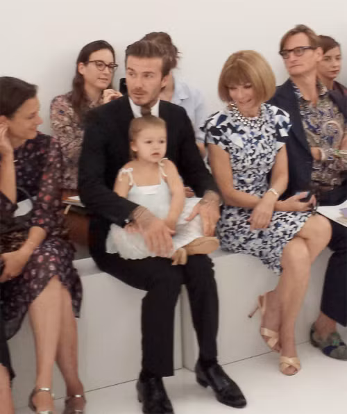 Harper ngồi gọn trong lòng bố khi cả hai bố con tới ủng hộ mẹ Vic ra mắt bộ sưu tập mới tại Tuần lễ thời trang New York tuần trước. Bà Anna Wintour, với mái tóc bob kinh điển và mặc váy họa tiết ngồi bên cạnh Becks, mỉm cười nhìn Harper. Ảnh: Huff.