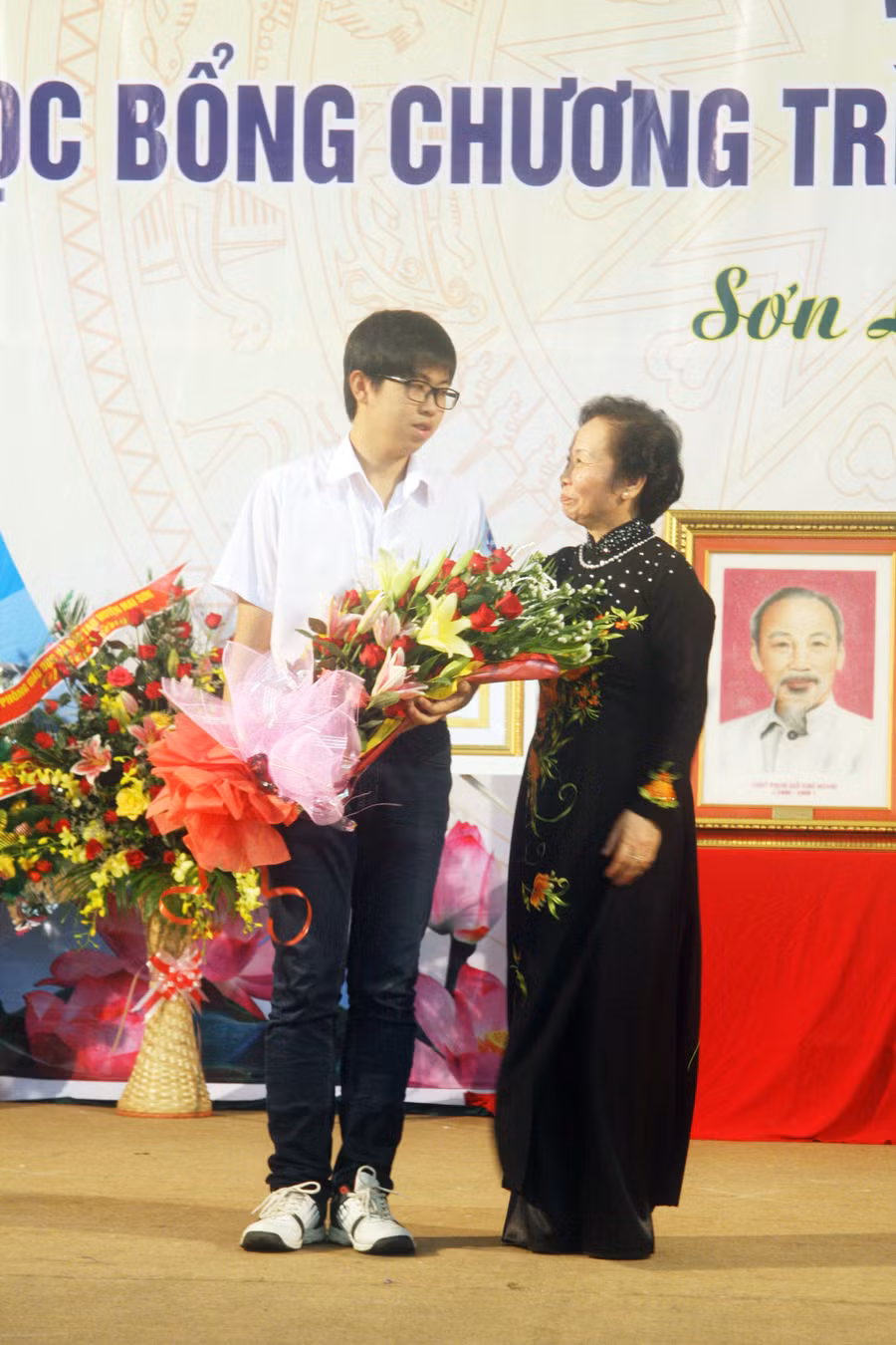 Ngô Phi Long lắng nghe lời dặn dò của Phó Chủ tịch nước Nguyễn Thị Doan nhân dịp trở lại trường, dự khai giảng năm học 2013 – 2014 và nhận quà tặng của Phó Chủ tịch nước