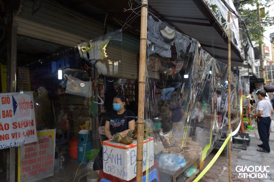 Tiểu thương bán hàng sau lớp tấm chắn bằng nilong.