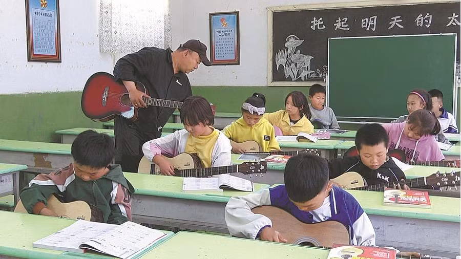 Song Hao dạy học sinh chơi guitar trong một trường tiểu học ở Gaozhuang thuộc Zhongwei, khu tự trị Ningxia Hui. Ảnh: China Daily