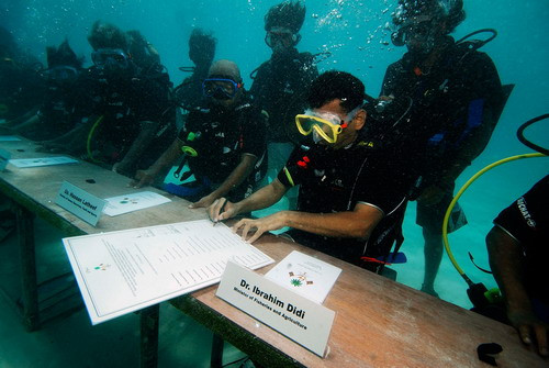 Maldivian Minister of Fisheries and Agriculture Ibrahim Didi signs a declaration calling on countries to cut down carbon dioxide emissions ahead of a major U.N. climate change conference in December, in the Maldives, October 17, 2009. The Maldivian president and ministers held the world’s first underwater cabinet meeting, in a symbolic cry for help over rising sea levels that threaten the tropical archipelago’s existence. (REUTERS/Maldives Government)