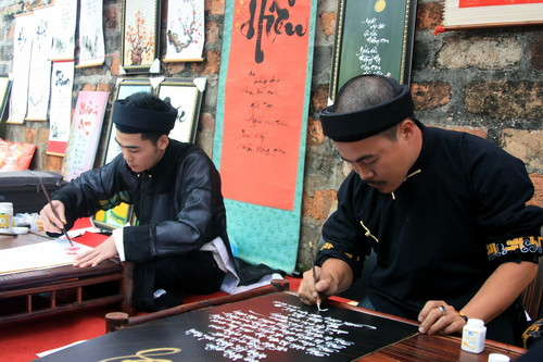 Hai nhà thư pháp trẻ này đang chăm chú hoàn thành tác phẩm của mình. Ảnh, gdtd.vn