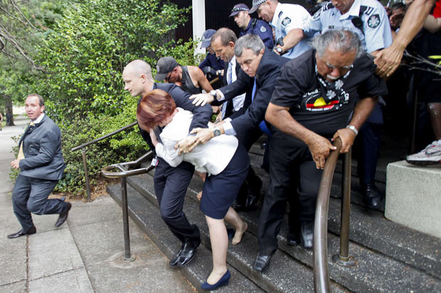 Những hình ảnh ấn tượng trong tuần ảnh 8 Australian Prime Minister Julia Gillard is bundled out of a restaurant by security service agents after it was surrounded by furious Aboriginal rights protesters in Canberra. Gillard and opposition leader Tony Abbott were stranded in The Lobby restaurant as dozens of demonstrators from a protest against Australia Day, which marks the arrival of British settlers in 1788, converged on the hotel...