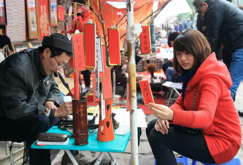 Nhà thư pháp Cao Sơn Hà đang viết chữ trên những chiếc khánh xinh xinh cho Khuê. Ảnh, gdtd.vn