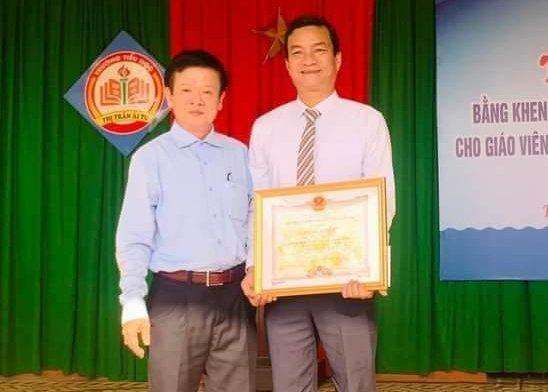 Phó Giám đốc Sở GD&amp;ĐT Quảng Trị - ông Phan Hữu Huyện trao Bằng khen của Chủ tịch UBND tỉnh tuyên dương thầy giáo Bùi Văn Quý.