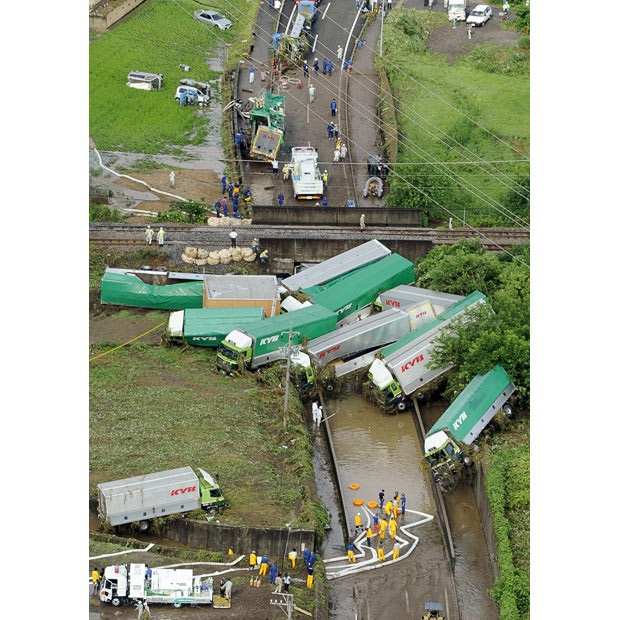 Police and rescue workers look at a pile of empty lorries that were washed away by floodwater in Kani, Gifu prefecture, western Japan. Torrential rains have caused flood and landslides in southern and western Japan