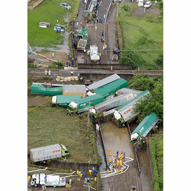 Police and rescue workers look at a pile of empty lorries that were washed away by floodwater in Kani, Gifu prefecture, western Japan. Torrential rains have caused flood and landslides in southern and western Japan