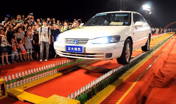 A driver sets a new Guinness World Record by driving along two rows of beer bottles for 60 metres. Li Guiwen, an army driver from Beijing, set the record at a record-setting event hosted by China Central Television and the Guinness World Record Office. He drove along two beer ’roads’ composed of 1,798 bottles that had been set up in Wenzhou, eastern China’s Zhejiang province. Li drove along the two standing tracks for 60.19 metres in a time of 8m 28s. He had previously attempted the same stunt last year but failed after wet weather caused his right tyre to slip