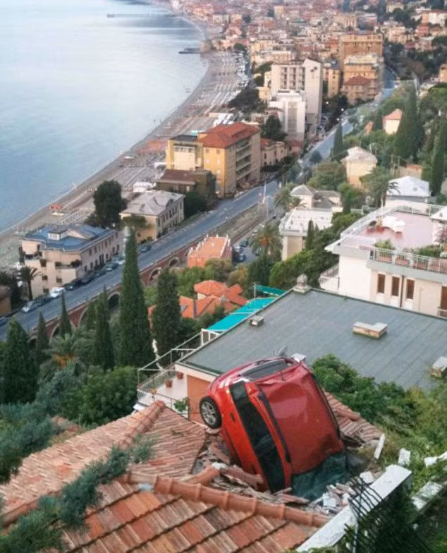 Red Fiat plunged through a barrier and landed on top of this house after its owner failed to put on her handbrake Read more: http://www.dailymail.co.uk/news/worldnews/article-1297077/What-happened-woman-driver-tried-park-car-stopped-admire-view.html#ixzz0uaxmvs6v