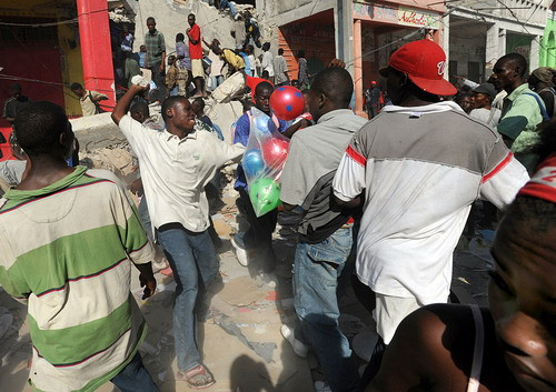 A mob of Haitians reach out as goods are thrown from a nearby shop in the downtown business district 