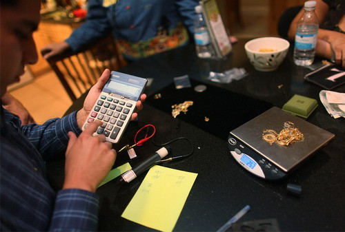 Pedro Linares uses a calculator to determine how much the company he works for, Fast Cash Gold Parties, will pay for the gold jewelry that he is weighing on October 30, 2009 in Hialeah, Florida. As the price of gold remains high, the company is busy setting up these modern day Tupperware parties to buy people’s unwanted gold in their homes