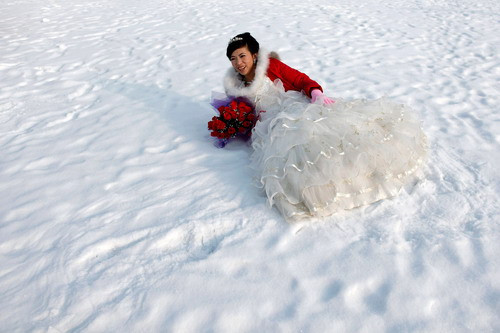 A bride poses for a photograph after a group wedding ceremony during the 26th Harbin International Ice and Snow Festival in Harbin, Heilongjiang province
