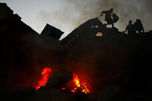 Scavengers climb across the rubble of quake-damaged buildings in downtown Port-au-Prince, Sunday, Jan. 17, 2010. Haitian police scattered hundreds of stone-throwing looters.