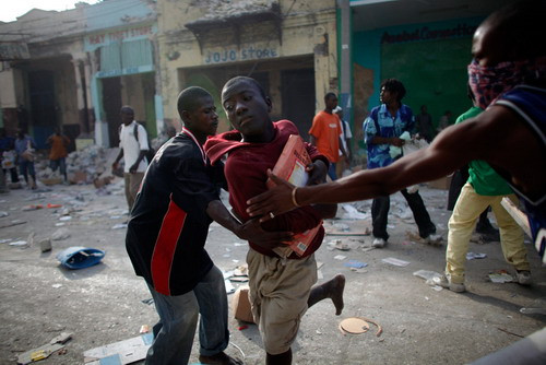Looters fight for products at a business area in Port-au-Prince January 16, 2010. Four days after a massive quake killed up to 200,000 people and wrecked most of the capital Port-au-Prince, hundreds of thousands of Haitians were still desperately waiting for assistance as scavengers and looters preyed on shattered buildings in the widespread absence of authority and order.