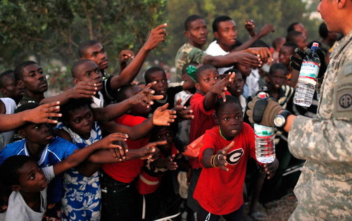 Survivors of Tuesday’s earthquake extend their arms as U.S. troops with the 82nd Airborne Division distribute water in Port-au-Prince, Sunday, Jan. 17, 2010. The troops gave out over 9,000 bottles of water and 2,000 meals Sunday. 