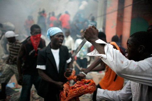 A man with a knife and other looters fight for goods taken from a destroyed store in downtown Port-au-Prince
