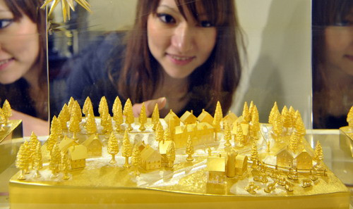 A Japanese girl admires a gold model named 