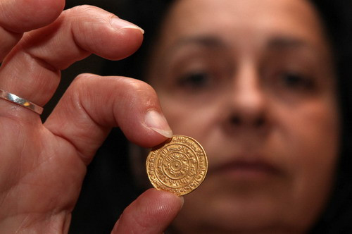 Hava Katz, the head of the national treasures of Israel’s Antiquities Authority, holds up a 1,000-year-old gold coin minted in Egypt and dated 1,095 AD, supposedly brought to Jerusalem by Muslim pilgrims, during an exhibition at the Davidson Archeological center in Jerusalem’s Old city 