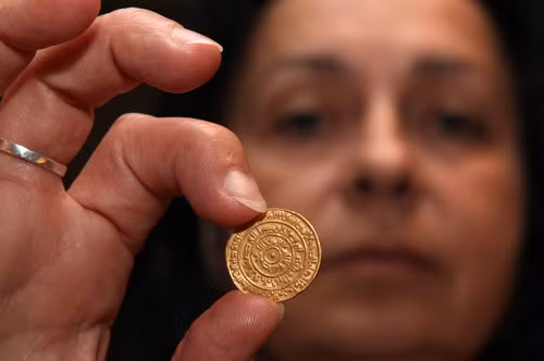 Hava Katz, the head of the national treasures of Israel’s Antiquities Authority, holds up a 1,000-year-old gold coin minted in Egypt and dated 1,095 AD, supposedly brought to Jerusalem by Muslim pilgrims, during an exhibition at the Davidson Archeological center in Jerusalem’s Old city 