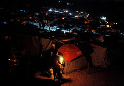 A boy holds a candle at a camp for earthquake survivors in Port-au-Prince, Haiti, Sunday,