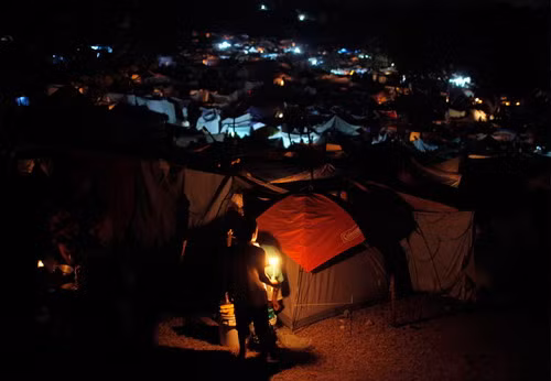 Một cậu bé cầm nến tại một lều tạm A boy holds a candle at a camp for earthquake survivors in Port-au-Prince, Haiti, Sunday,