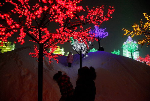 A girl stands amongst brightly lit tree lights at the Harbin International Ice and Snow festival in Harbin, China on Wednesday, Jan. 6, 2010. (AP Photo/Ng Han Guan)
