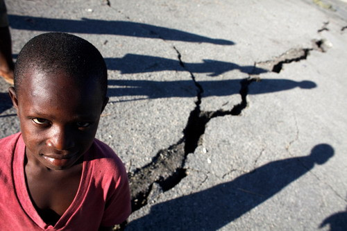 Children walk past a crack caused by the earthquake in a street in Port-au-Prince