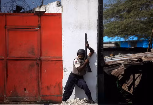 Một cảnh sát Haiti trong tư thế... sẵn sàng chiến đấu với nạn cướp bóc ở Port-au-Prince Looters run during a police assault, January 17, 2010 near the Hypolite Market in Port-au-Prince. Hundreds of rioters ransacked Hyppolite market in the heart of the devastated city as survivors besieged hospitals and make-shift field clinics, some carrying the injured on their backs or on carts