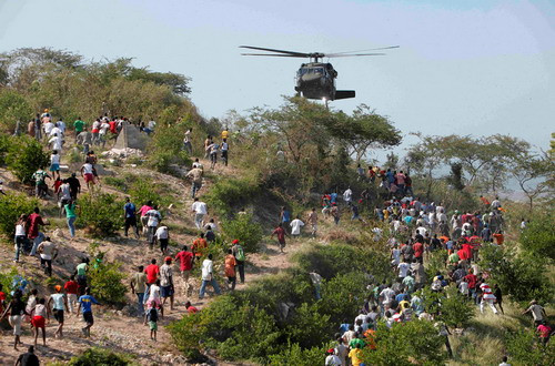 People run toward a U.S. helicopter as it makes a water drop near a country club used as a forward operating base for the U.S. 82nd Airborne Division in Port-au-Prince, Haiti, Saturday, Jan. 16, 2010. Relief groups and officials are focused on moving aid flowing into Haiti to survivors of the powerful earthquake that hit the country on Tuesday