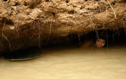 A woman wades deep under a river bank to collect mud to pan for gold in Pidie district in Indonesia’s Aceh province November 2, 2009. Residents in the area engaged in traditional gold mining can get about 1.5-2 grams of gold and earn 275,000 rupiah ($28) per day
