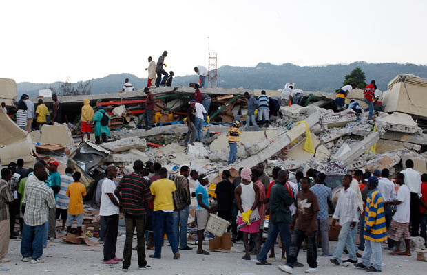 Máu và nước mắt thấm đẫm Haiti ảnh 3 People search for survivors among the debris of a collapsed building