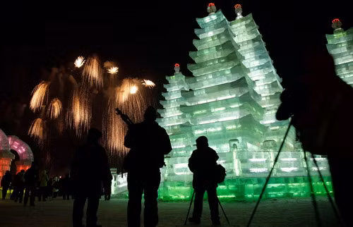 Du khách đứng xem pháo hoa tại một tác phẩm chùa tháp bằng băng Visitors watch fireworks display during the opening ceremony of the Harbin International Ice and Snow Festival