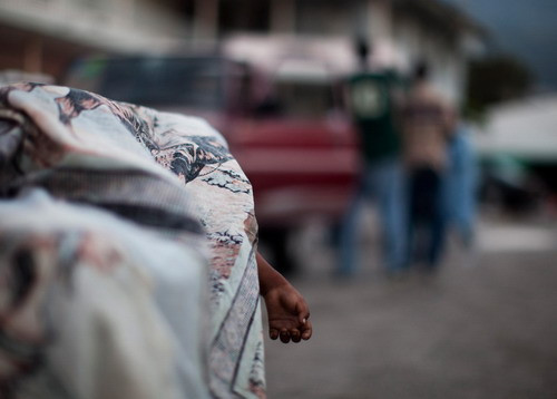 A young child’s dead body lies covered on a table outside the general hospital’s morgue on January 16, 2010 in Port-au-Prince