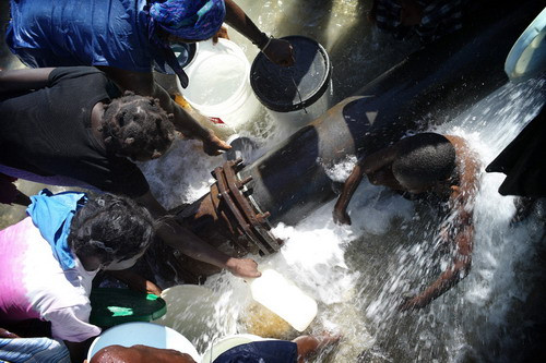 People take water after breaking a pipe, on January 16, 2010 in the shantytown 