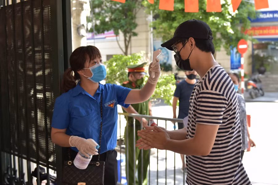 Tất cả người dân khi vào trong khu vực tiêm sẽ phải kiểm tra thân nhiệt và rửa tay sát khuẩn.