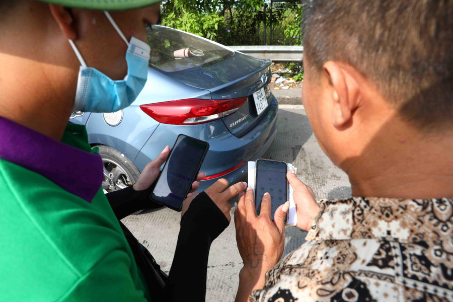 Nhân viên ETC dán thẻ và hướng dẫn các lái xe về cách nạp tiền vào tài khoản để đi vào làn không dừng.